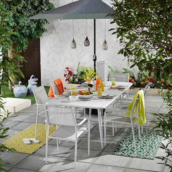 In einem sommerlichen Garten sind drei hübsche Solar Hängelampen an einem Schirm über einem Esstisch befestigt. Sie machen eine wunderschöne Deko.